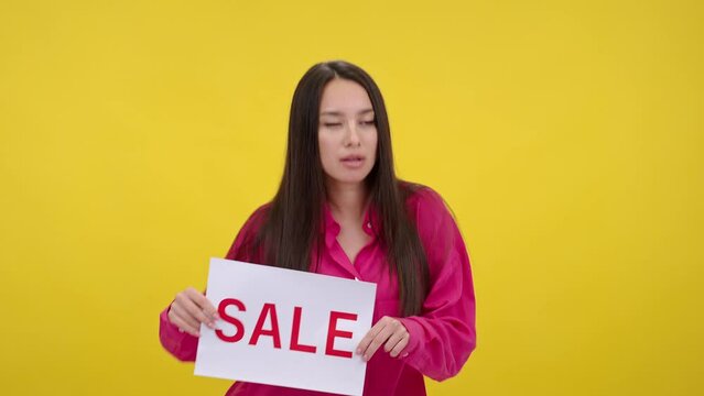 Woman dances funny holding sign with word Sale and laughs