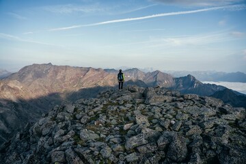 Hiker standing on a rocky mountain top wearing a protective helmet and a backpack