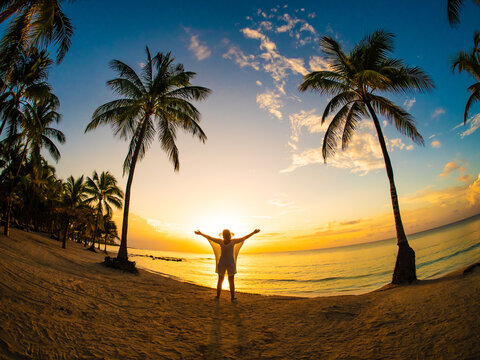 Woman walking on sunny, tropical beach at daybreak 
