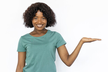 Fototapeta na wymiar Smiling Woman holding something on palm.Female African American model with curly hair in green T-shirt presenting and pointing with her hand to right and smiling.Advertising, social media concept