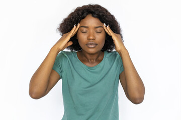 Young woman suffering from headache. Female African American model with curly hair in green T-shirt holding palms at temples because of headache. Fatigue, pain concept