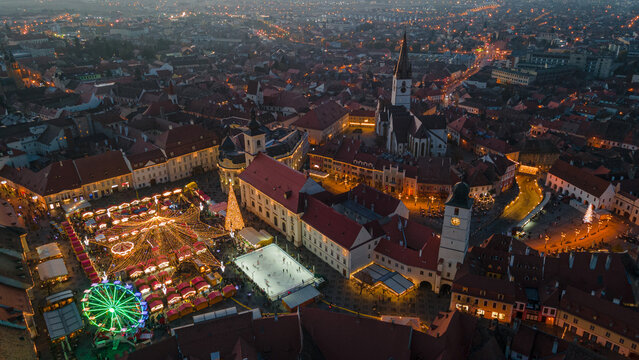 Landscape photography of Sibiu city center with the Christmas Fair, shot from a drone at higher altitude, at sunset with the city lightning on. Birds eye view over cityscape of Sibiu, Romania.