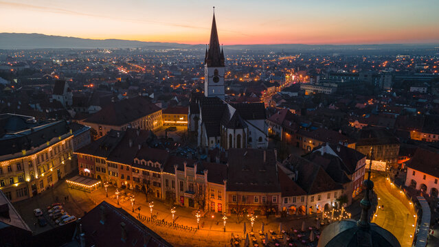 Birds eye view over historic city center of Sibiu, Romania at sunset. Aerial photography was shot from a drone at sunset with the Council Tower and a beautiful cityscape in view. 