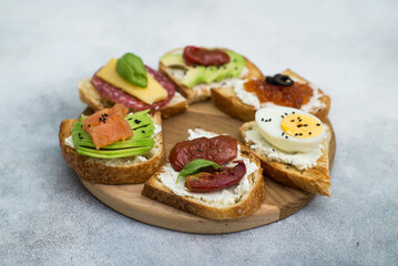 Variety of tapas sandwiches for aperetif on wooden on gray background. Top view.