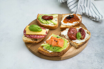 Variety of tapas sandwiches for aperetif on wooden on gray background. Top view.