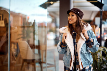 Fototapeta premium Happy woman looking at store windows while walking in city.