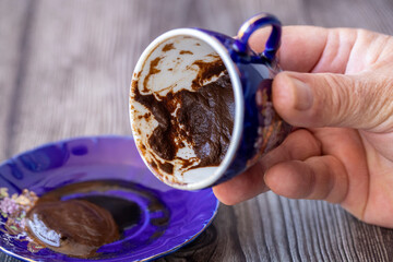 The fortune teller makes predictions on the coffee grounds on the table.
