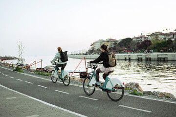 Two young woman cycling. They have backpacks. Kadıköy, İstanbul.