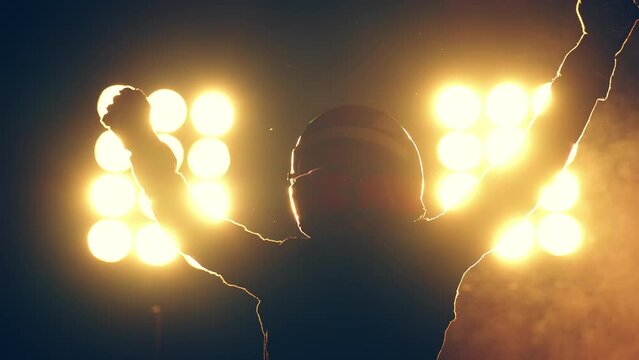 Silhouette of race car driver celebrating the win in a race against bright stadium lights. 100 FPS slow motion shot