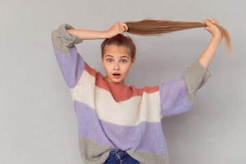 playful teen girl holding hair and open mouth in surprise