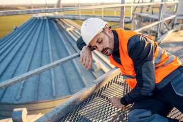 A tired metal construction worker is sleeping on his workplace.