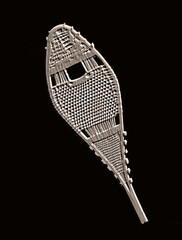 Old embossed snow shoe on a black background