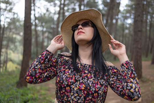 Young girl wearing hat and sun glasses. She is in forest.