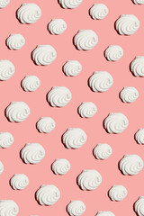A hard light pattern of a sweet meringue dessert pavlova on a bright colorful pink seamless background, top view