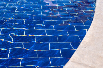 Klares Wasser im Pool mit dunkelblauen Fliesen. Kachelmuster im Freibad im Sommer bedeckt vom...
