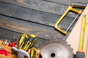 Meter, wooden planks, construction tools and circular saw blade on the carpenter workbench top view background with copy space.