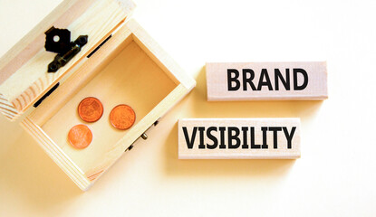 Brand visibility symbol. Concept words Brand visibility on wooden blocks. Beautiful white table white background. Wooden chest with coins. Business branding and brand visibility concept. Copy space.