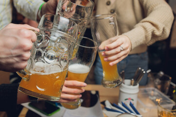 Four friends with a fresh beer in a Beer garden close-up on beer stein.