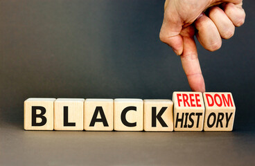 Black history and freedom symbol. Concept words Black history Black freedom on wooden cubes. Businessman hand. Beautiful grey table grey background. Black history and freedom concept. Copy space.