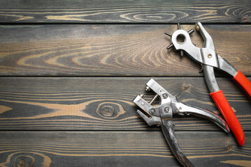 Riveter and hole puncher work tool on the wooden workbench flat lay background with copy space.