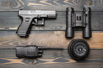 Security camera, binoculars, pistol gun and portable radio station on the table flat lay background. Security equipment concept background.