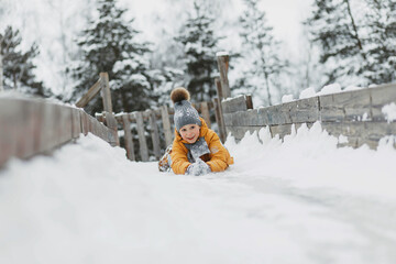 A girl rides down a wooden slide in winter