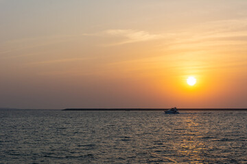 Amazing sunset in Dubai with colourful sky, calm sea and a small yacht 