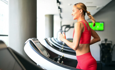 Young athletic beautiful woman training on a treadmill in the gym
