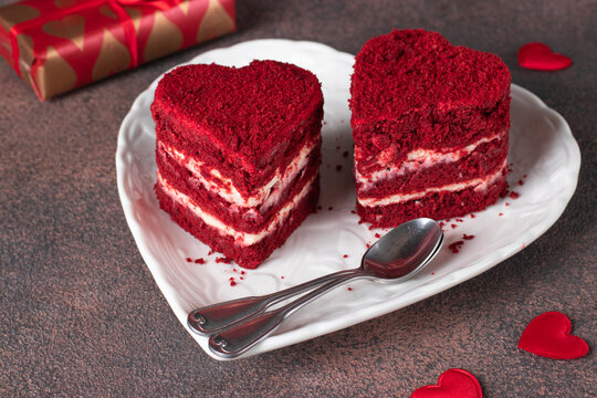 Two cakes Red velvet in the shape of hearts on white plate and gifts on brown background, Cake for Valentines Day