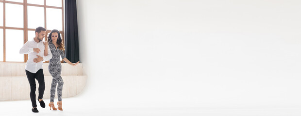 Banner young couple dancing social latin dance bachata, merengue, salsa. Two elegance pose in dance class with big window copy space