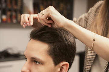 Fototapeta premium Barber shop men hairstyle. Young man getting a modern haircut. Hair salon master does hair styling client at barber shop. Men's fashion and style. Hair care, beauty industry, barber concept