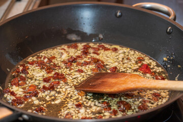 Fried onions with sun-dried tomatoes in a pan.