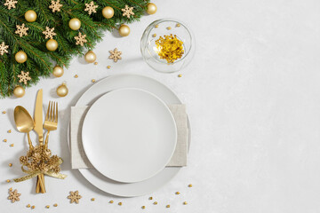 Christmas table setting with golden festive decorations and empty plate on gray background. Happy new year. Space for text. Winter concept. Top view, flat lay.