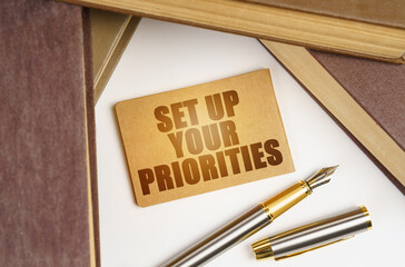 Next to the books lies a pen and a sign with the inscription - SET UP YOUR PRIORITIES