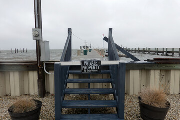 Wooden steps leading to a wooden dock with a private property, no trespassing sign on a stormy...