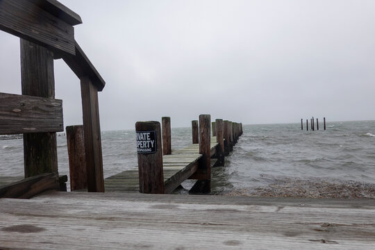 Rough Ocean Surf Pounds The Wooden Dock With A No Trespassing Sign At A Deserted Marina During A Storm