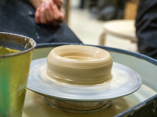 A close-up of a clay mold spinning on a potter's wheel. Handmade, craft, clay modeling, selective focus