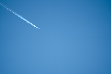 high altitude twin engine contrails (jet airplane vapour trails) across a deep blue clear sky