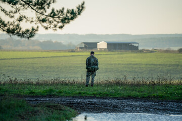 a soldier stands alone in open countryside 