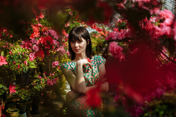 Obraz na płótnie Canvas Beautiful brunette in a garden of azaleas in a green dress