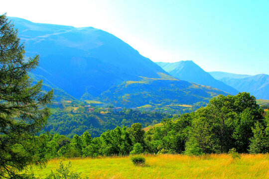 Magical view in Montemonaco at the powerful Sibillini mountains and their rough crests suffused with blue and green tones in the background and calm greenery and trees in the foreground