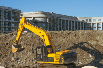 Excavator on earthworks at construction site. Backhoe on foundation work and road construction. Heavy machinery and construction equipment.