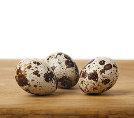 Obraz premium Quail eggs on a wooden table isolated on a white background.