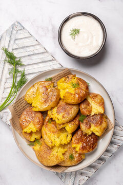 smashed potato on parchment paper with garlic sauce