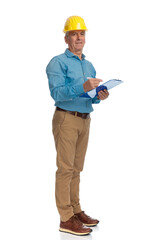 good looking old engineer with helmet holding clipboard and taking notes
