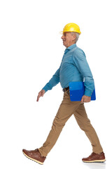 proud old engineer with safety yellow helmet and clipboard walking