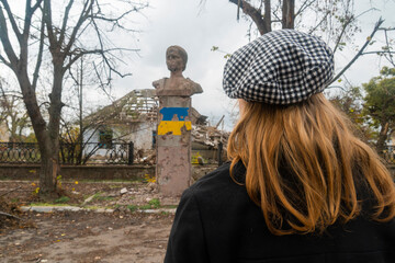 War in Ukraine. 2022 Russian invasion of Ukraine. The girl looks at the monument damaged by...