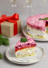 Traditional Russian New Year's salad. A portion of puff salad herring under a fur coat on a white plate. Russian national cuisine. Selective focus.