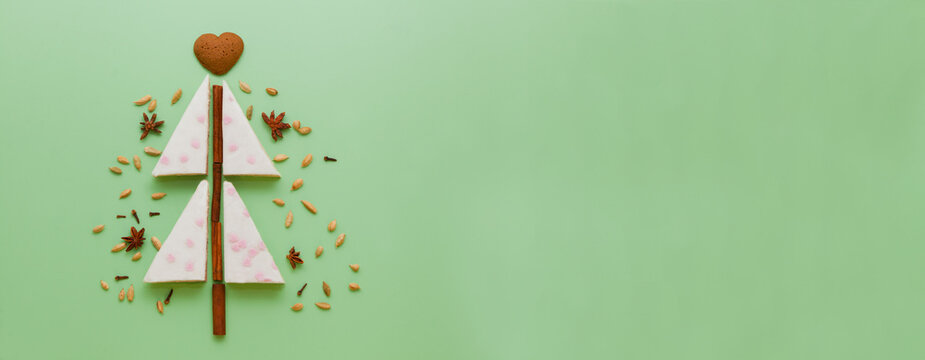 banner with white cake christmas tree shaped and Gingerbread, anise, cinnamon pie flat lay on green