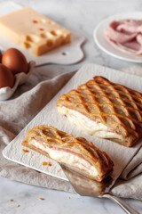 Puff with ham and cheese cut on a rectangular plate on a kitchen table